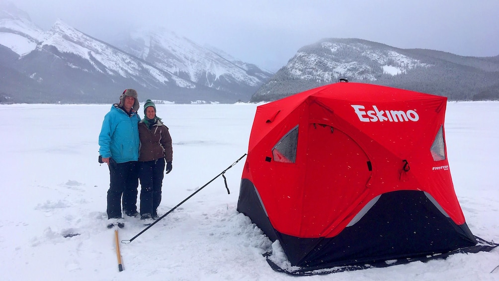 Show item 3 of 4. Two people stand next to a tent on a frozen lake