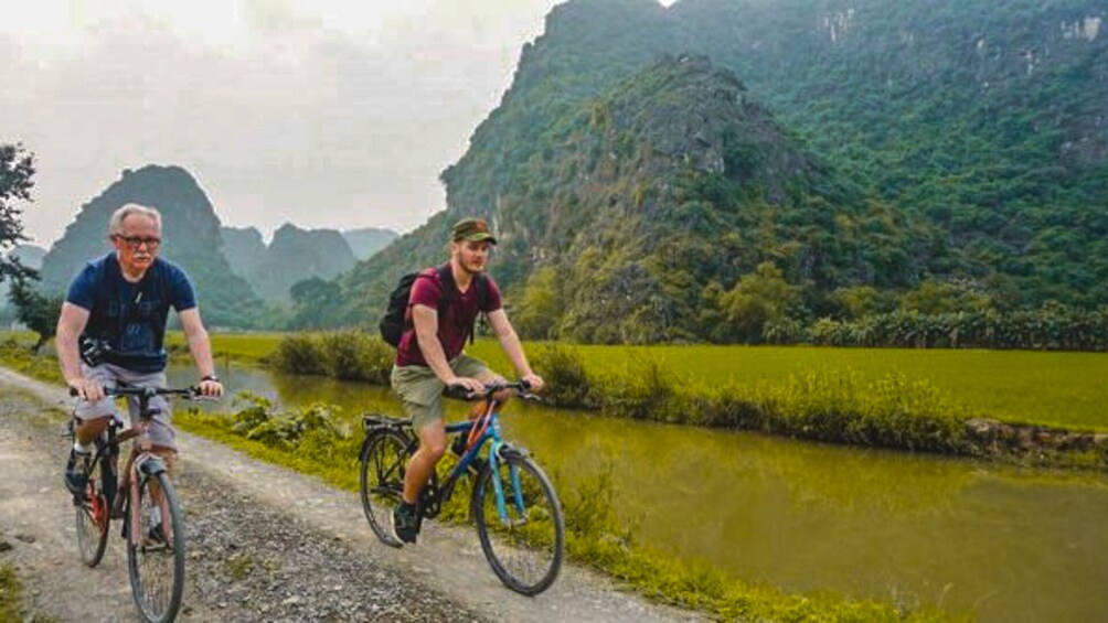 Ten men bike along water in Ninh Binh, Vietnam