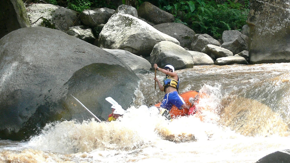 Group white water rafting through a rapid down Mae Taeng River