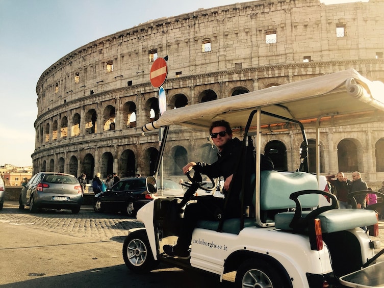 Man in golf cart in front of the Colosseum