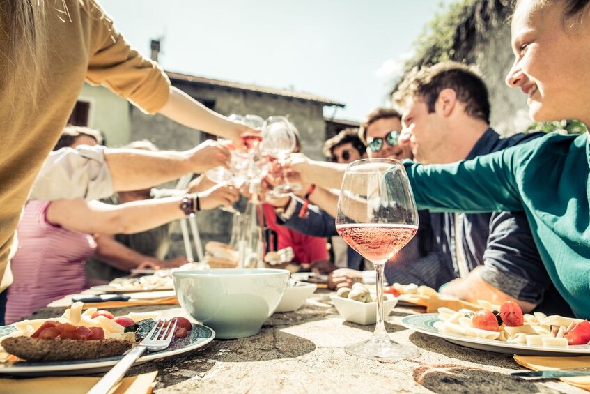 Show item 2 of 5. People raise wine glasses over dinner table in Cortona, Italy