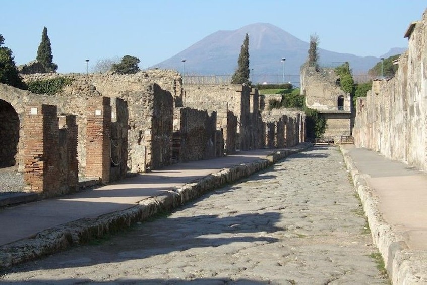 Road surrounded by ruins and Mount Vesuvius in Pompeii, Italy