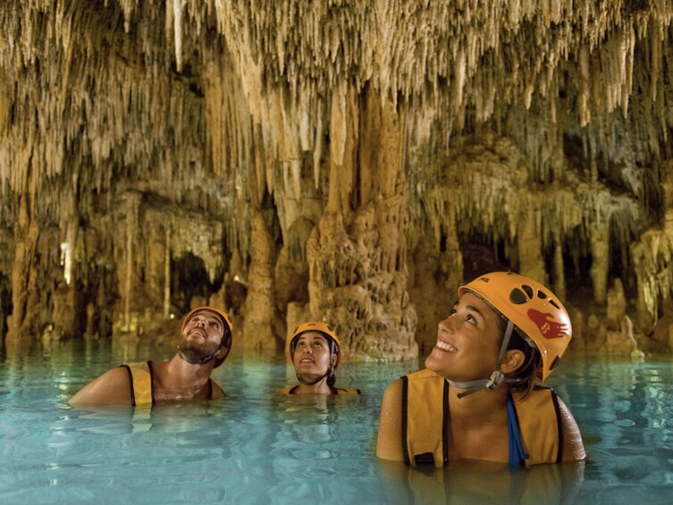 Group swimming in the crystal-clear waters of an underground river at Xplor