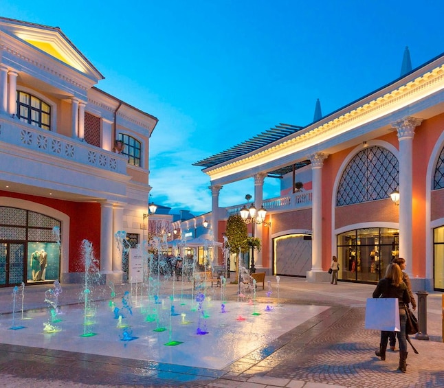 Castel Romano shopping mall lit up at dusk