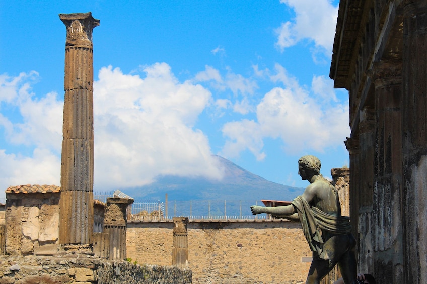 Statue and columns in Pompeii with Mount Vesuvius in the background