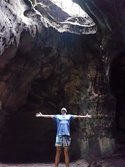 Man stands in cave with outstretched arms in Presidente Figueiredo, Brazil