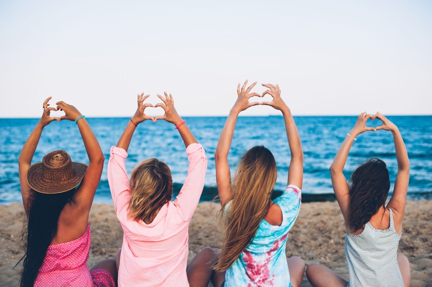 Four girls make heart symbol with hands at Niagara Falls
