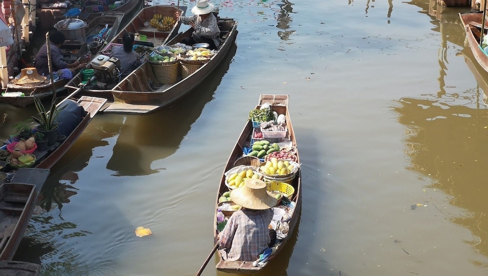 Woman in boat filled with produce at Tha Kha Floating Market