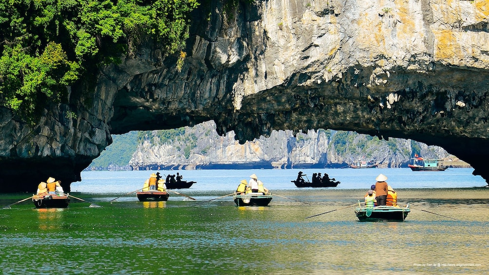 Kayakers under low hanging rocks in Bai Tu Long Bay
