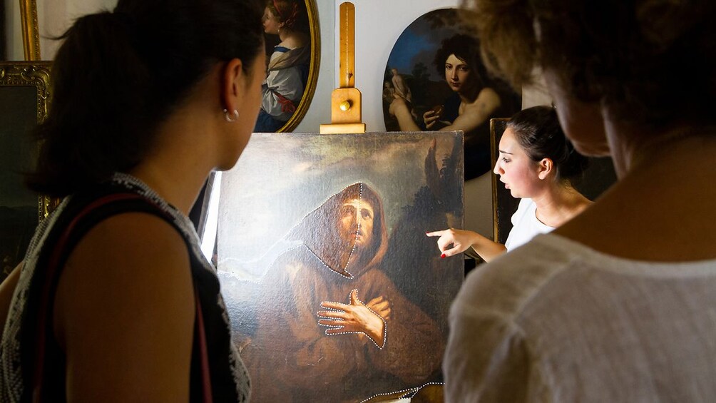 Guide speaks to group about classic painting