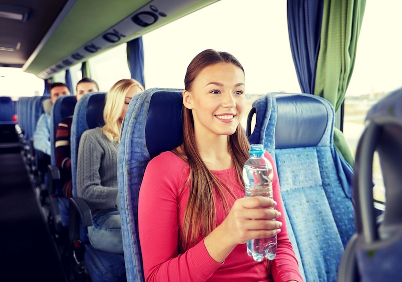 Woman with bottle of water smiles on bus to Niagara Falls