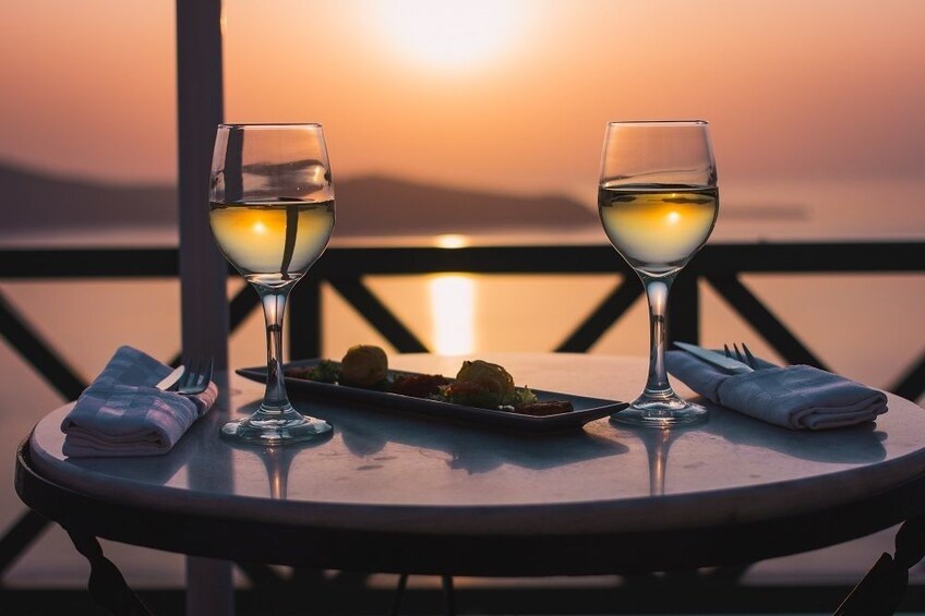 Two glasses of wine and appetizers on table overlooking the Mediterranean at sunset 