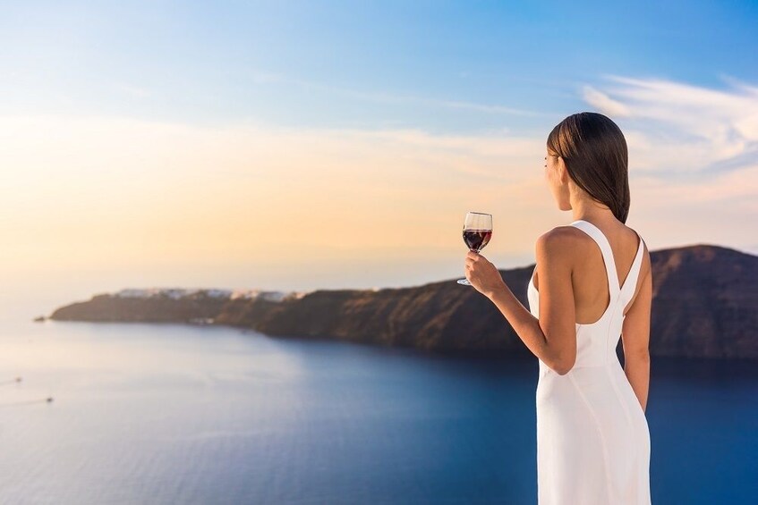 Woman in white gown with wine glass overlooking the Mediterranean 