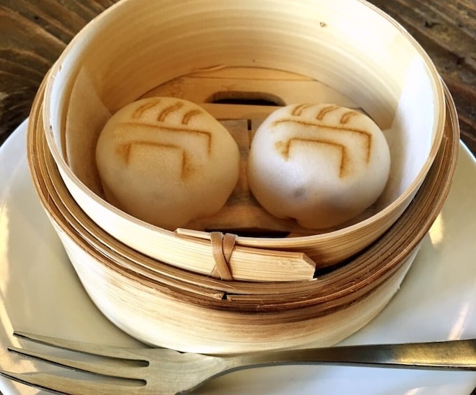 Two pork buns in bamboo steamer