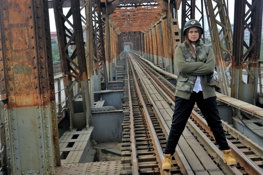 Girl with helmet stands on train tracks in Hanoi, Vietnam