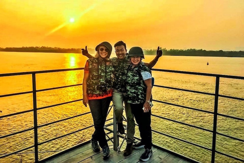 Tourists pose in front of the Red River at sunset