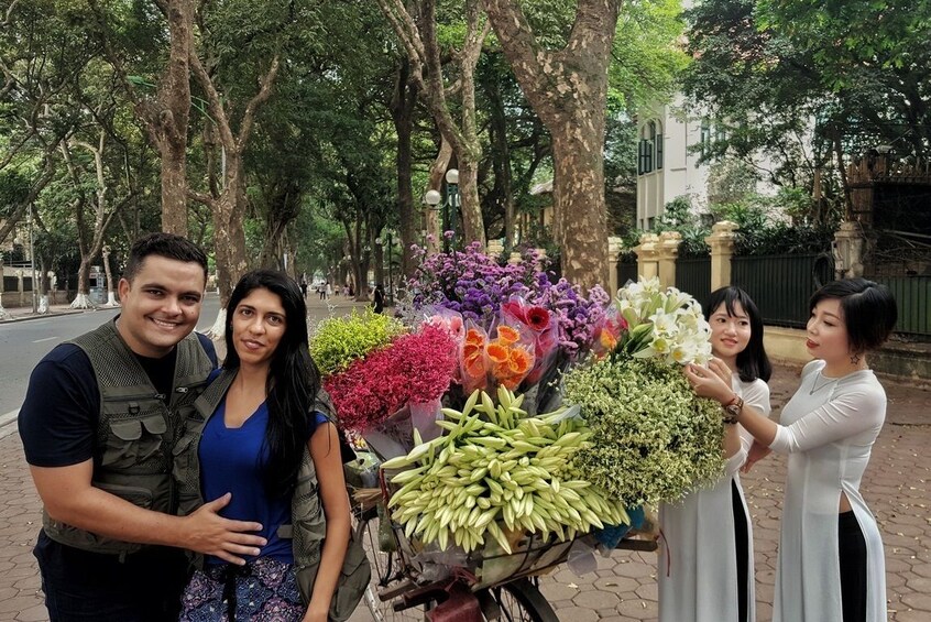 Couple pose with basket flowers and flower sellers in Vietnam