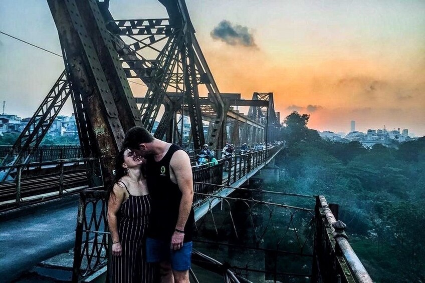 Couple pose at Long Biên Bridge at sunset