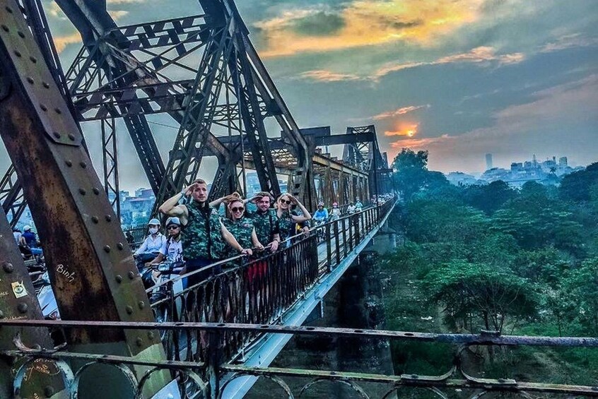 Tour group pose on Long Bien Bridge at sunset
