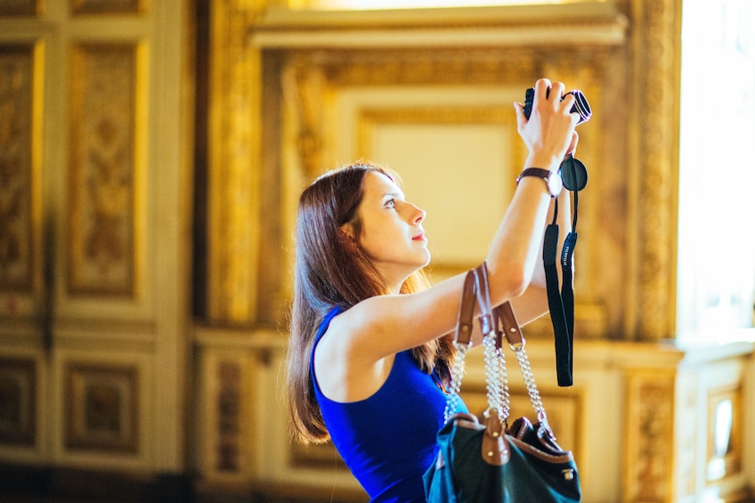 Woman takes photograph inside gilded room