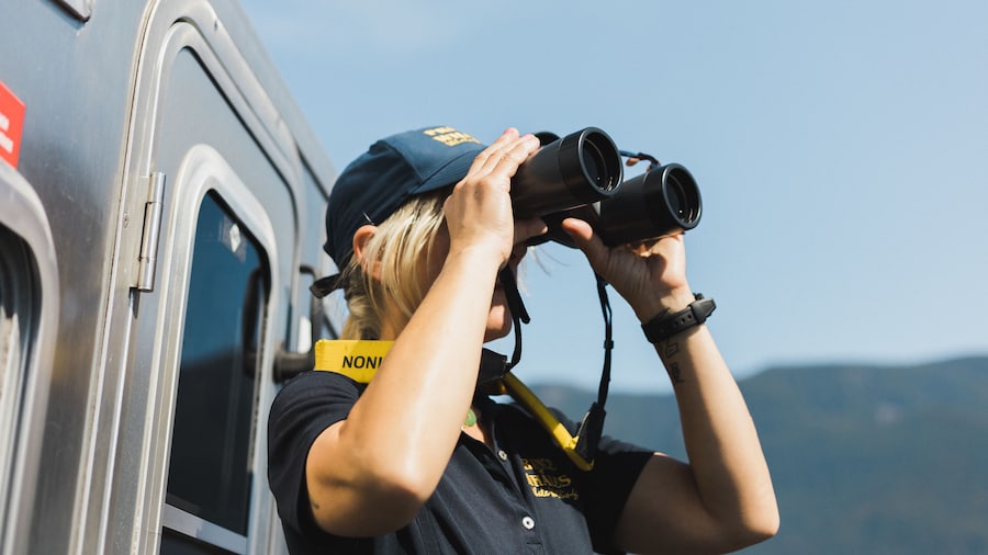 Woman looks through binoculars off whale boat British Columbia