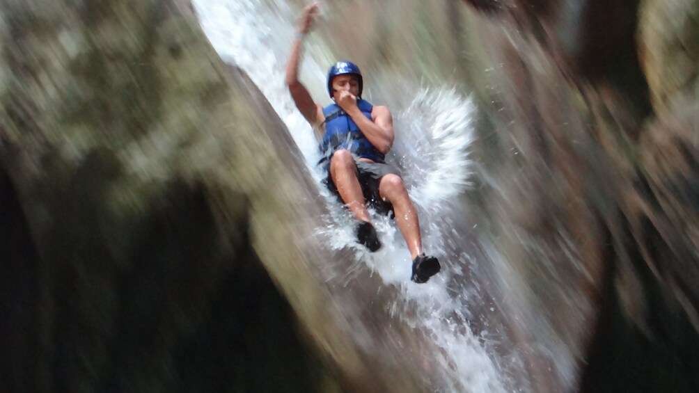 Man jumps in front of a waterfall in the Dominican Republic