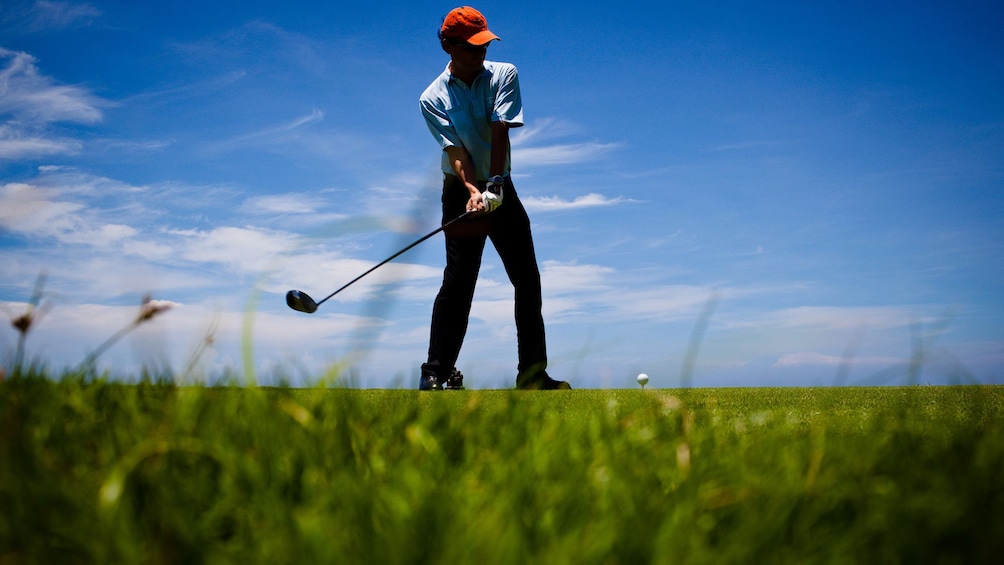 View from ground of man getting ready to swing golf club