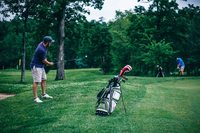 Man hits golf ball with golf bag nearby in Vietnam