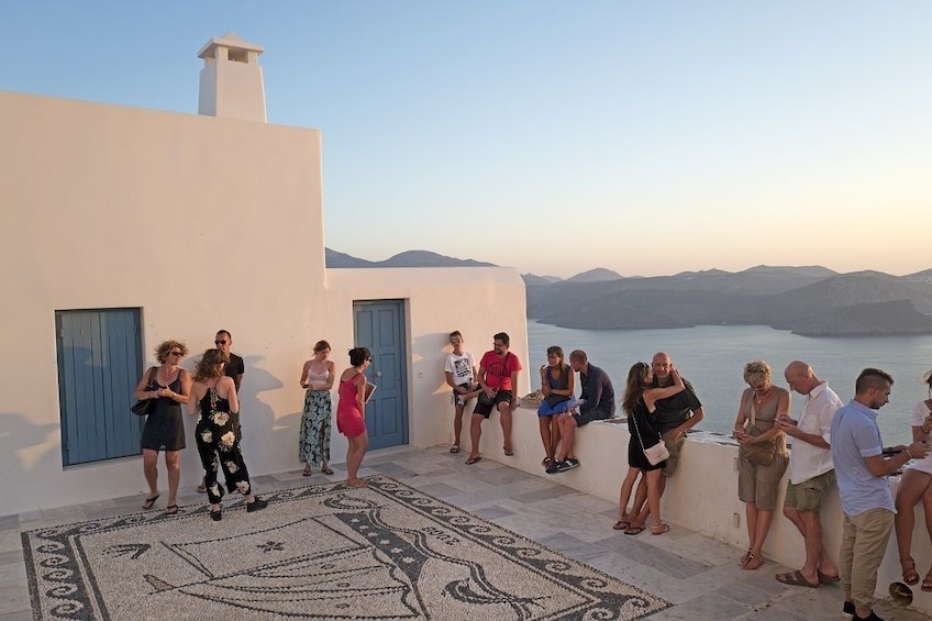 Tour group stands at balcony on top of building in Greece