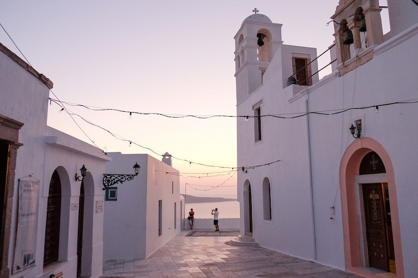 Greek alley looking out towards sun setting over the water