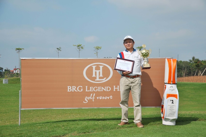 Golfer poses with trophy and certificate at BRG Legend Hills Golf Resort