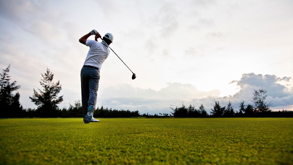 View down golf course of golfer swing club