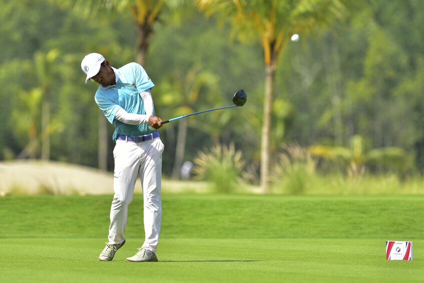 Golfer mid-swing at Vietnamese golf course