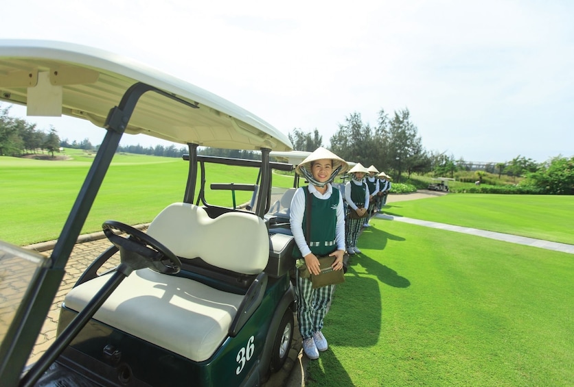 Workers stand next to golf carts at a golf club in Vietnam