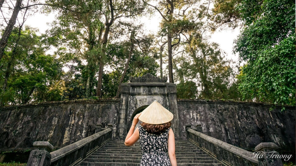 Woman walks toward stone bridge in Hue, Vietnam