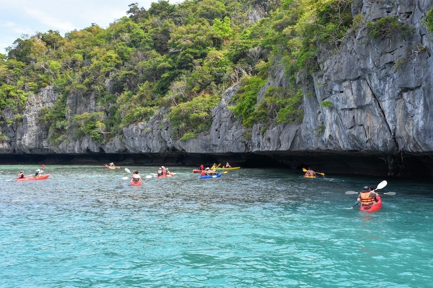 People kayak towards shallow caves in Thailand