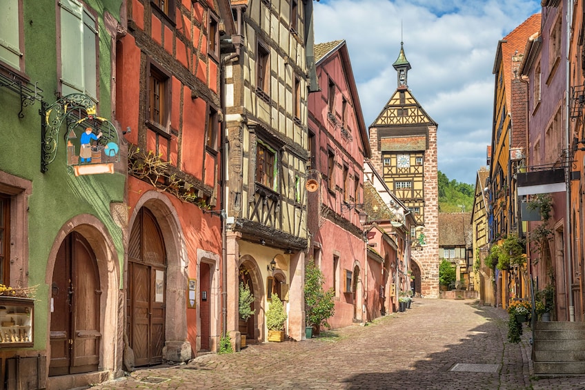 Colorful french houses on a Riquewihr village street and Dolder Tower
