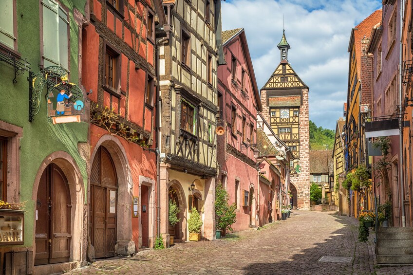 Colorful french houses on a Riquewihr village street and Dolder Tower