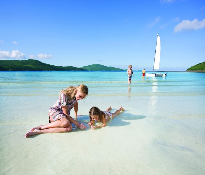 Woman and girl sit on the beach of Hamilton Island