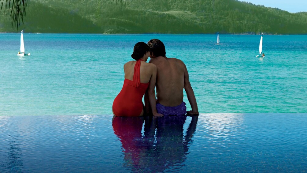Couple sit together on edge of infinity pool on Hamilton Island