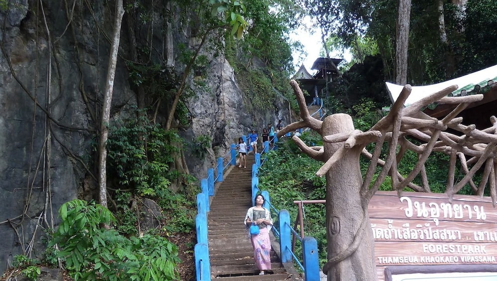Woman stands on stairs at the entrance of Thung Theo Forest Natural Park