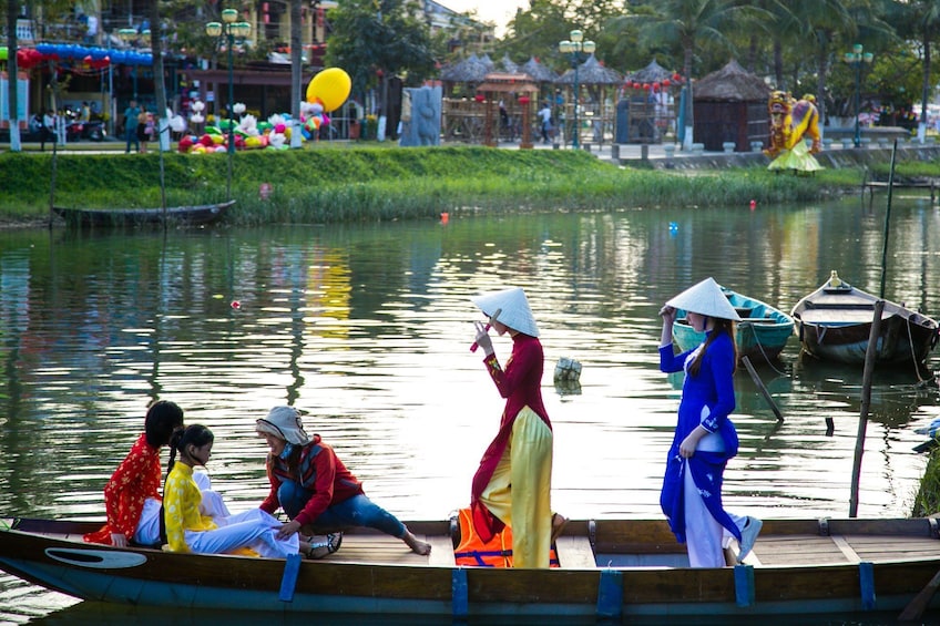 Women in traditional Vietnamese dresses on a boat at Hoi An Impression Theme Park