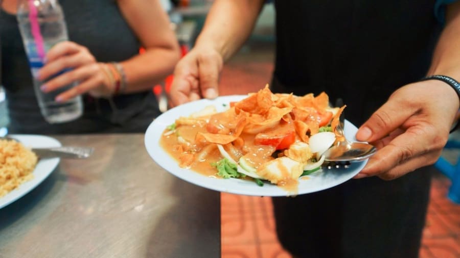 Man holds plate of food at Bangkok market
