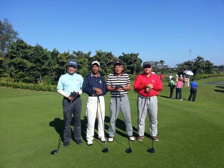 Four golfers pose on the golf green in Vietnam