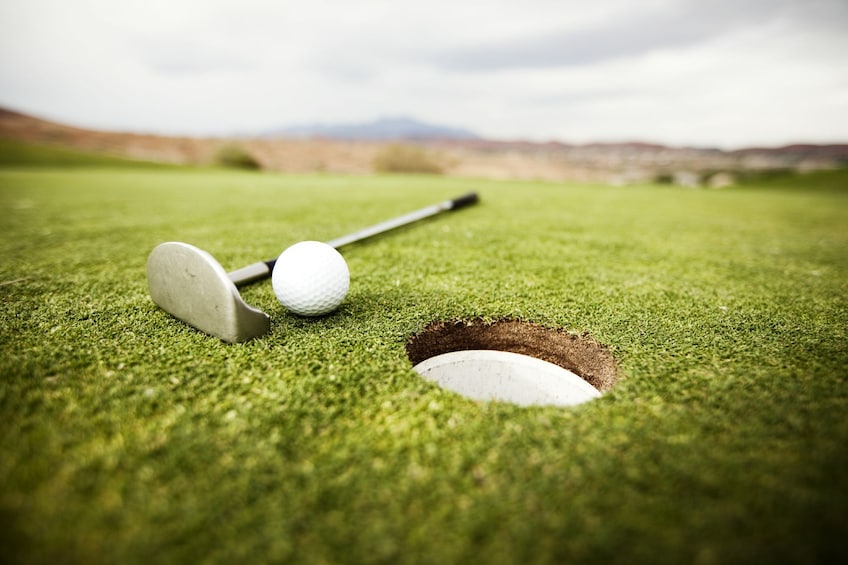 Closeup of putter, golf ball and hole