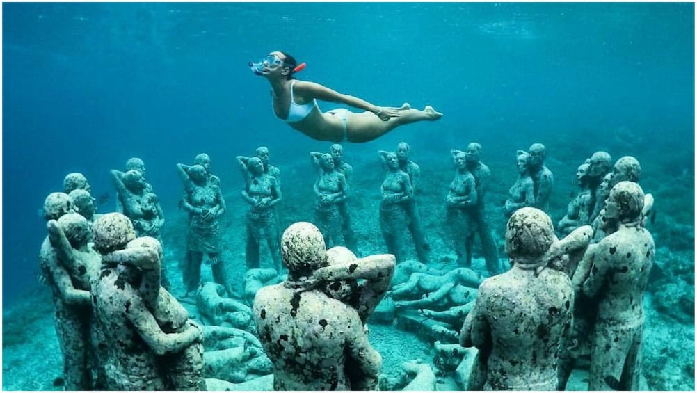 Show item 3 of 7. Woman snorkels above Gili statues in Bali