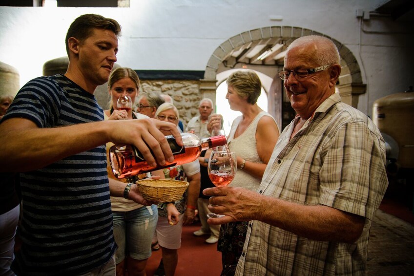 Man pours glass of wine for fellow tourist in Mallorca