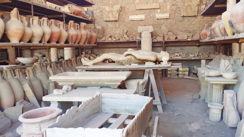 Petrified Pompeiian person surrounded by pots in workshop area