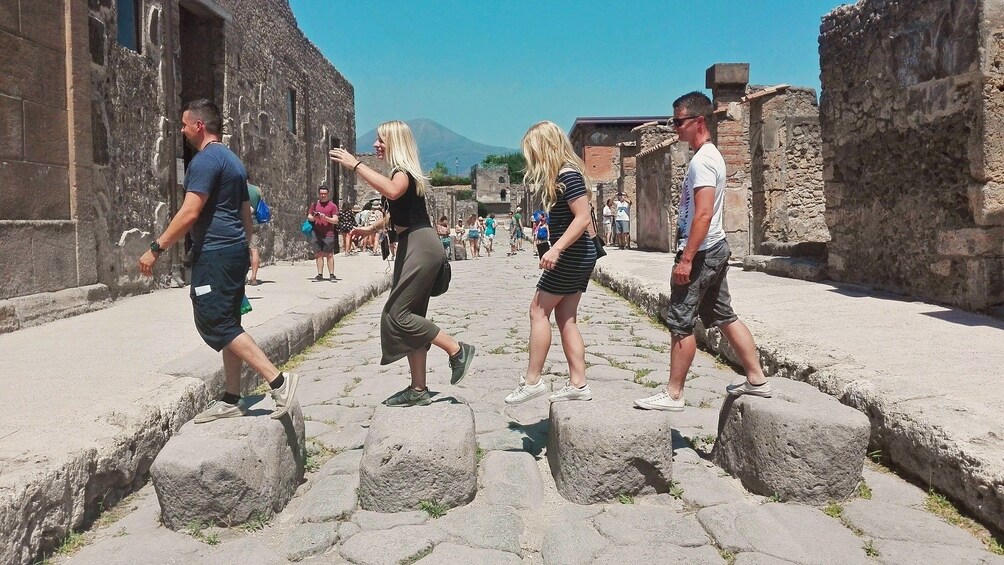 Tourists walk across stones on road in Pompeii