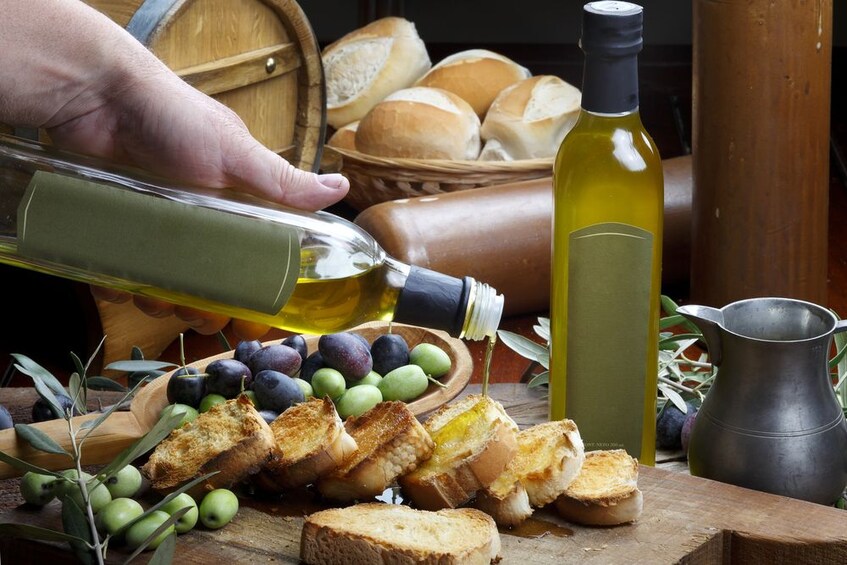 Person pours olive oil on slices of bread
